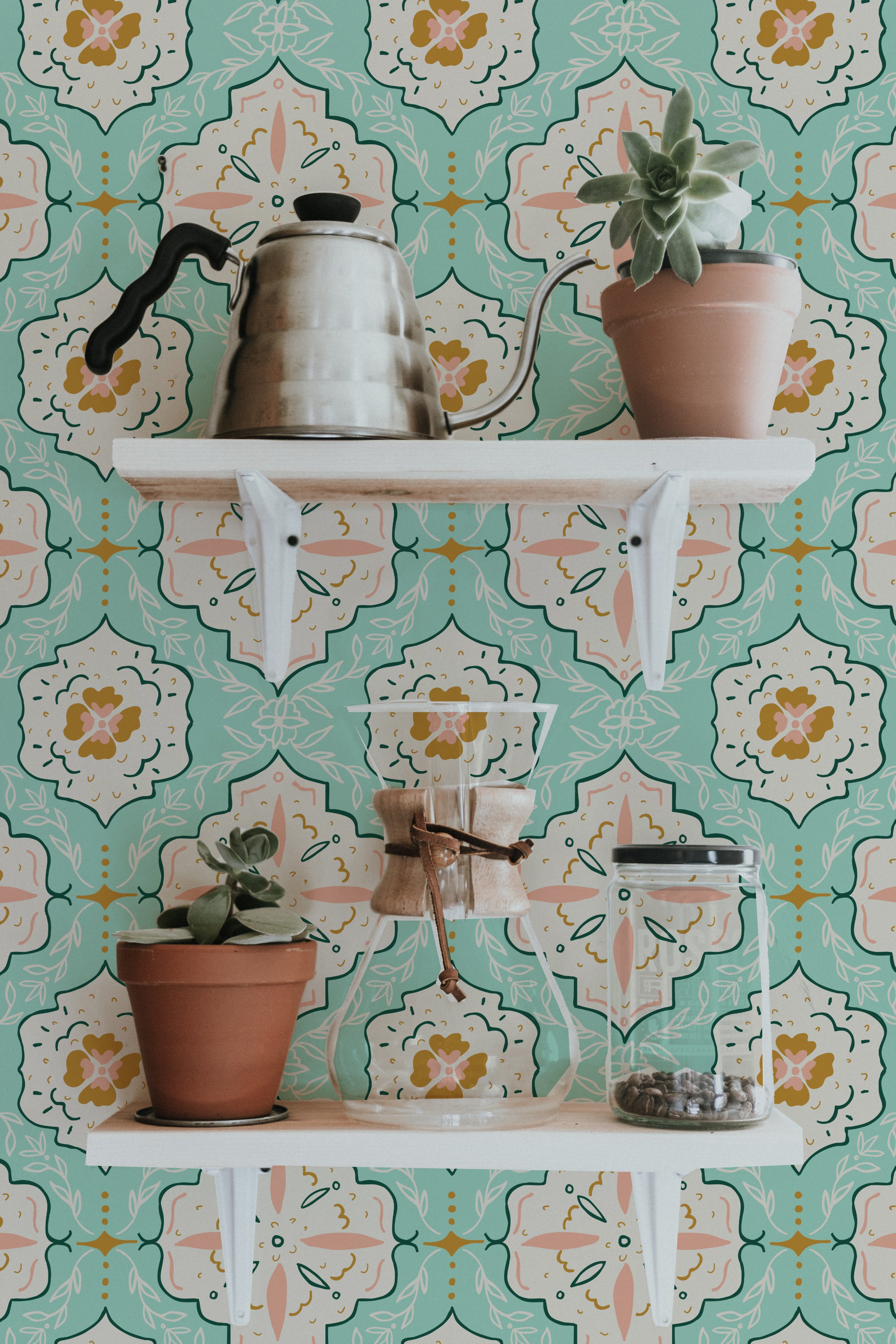 Wall-mounted shelves against a background of Fatima Tile Wallpaper with a detailed Moroccan tile design in turquoise, adorned with various houseplants and kitchen utensils.