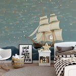 Playful child's room with ocean mural depicting a sailing ship, furnished with a small table and chairs and draped canopy bed.