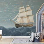 Adventurous child's room with sailing ship wallpaper, modern children's furniture including a rocking chair and patterned bedding.