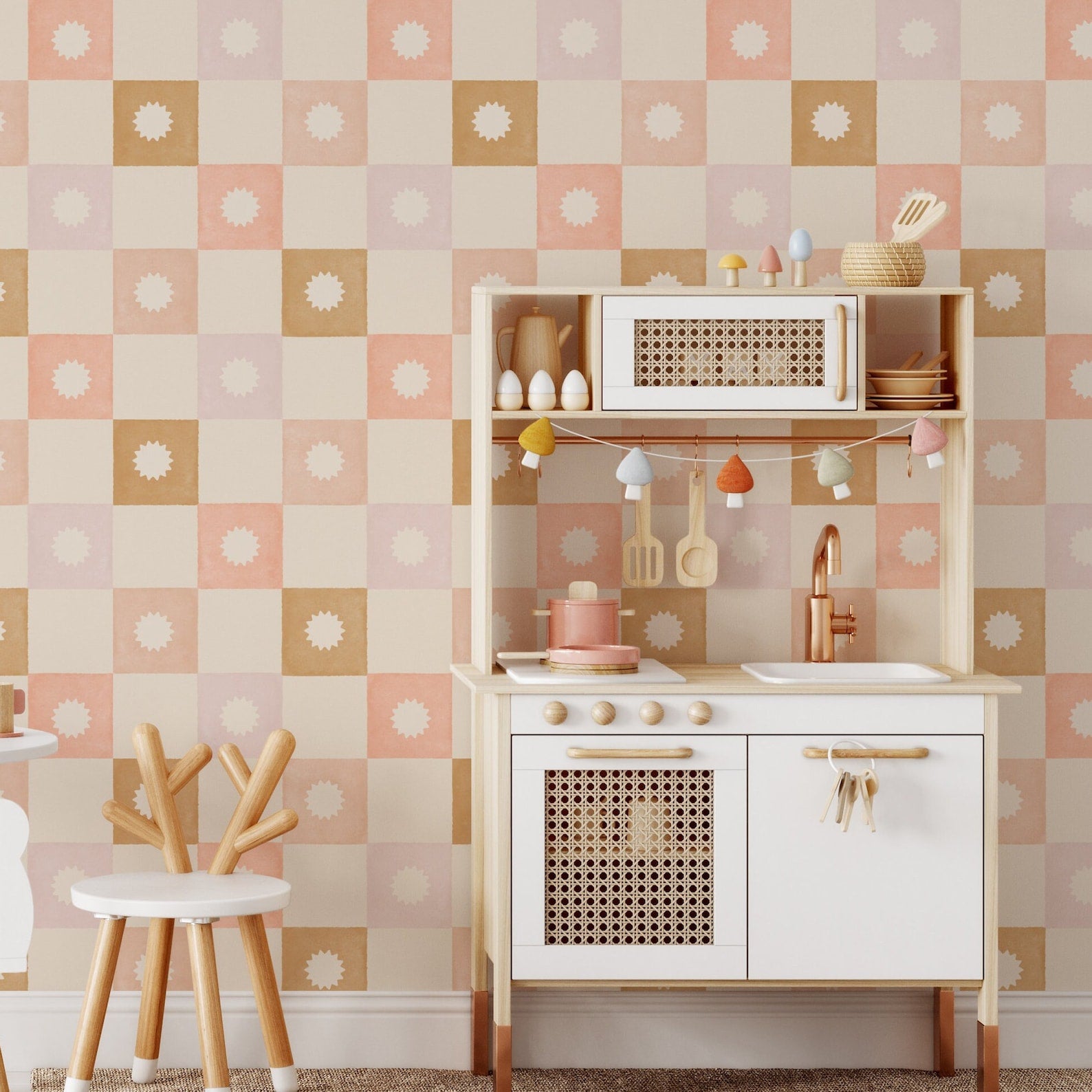 Children’s play area decorated with Coralie Wallpaper, featuring pastel-toned squares and sunburst patterns. The space is furnished with a small wooden play kitchen and child-sized furniture, making it bright and cheerful.