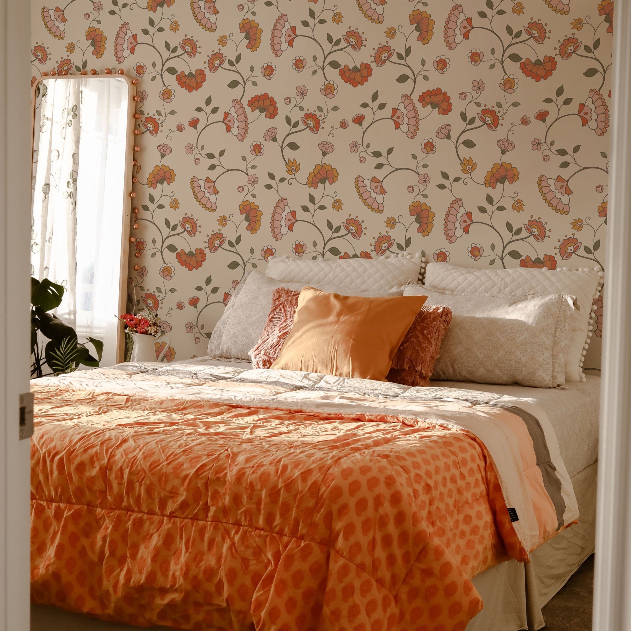 A cozy bedroom filled with natural light, adorned with the Retro Pattern Wallpaper. The room features a bed with an orange textured comforter and decorative pillows in shades of orange and cream, harmoniously blending with the room's warm color scheme