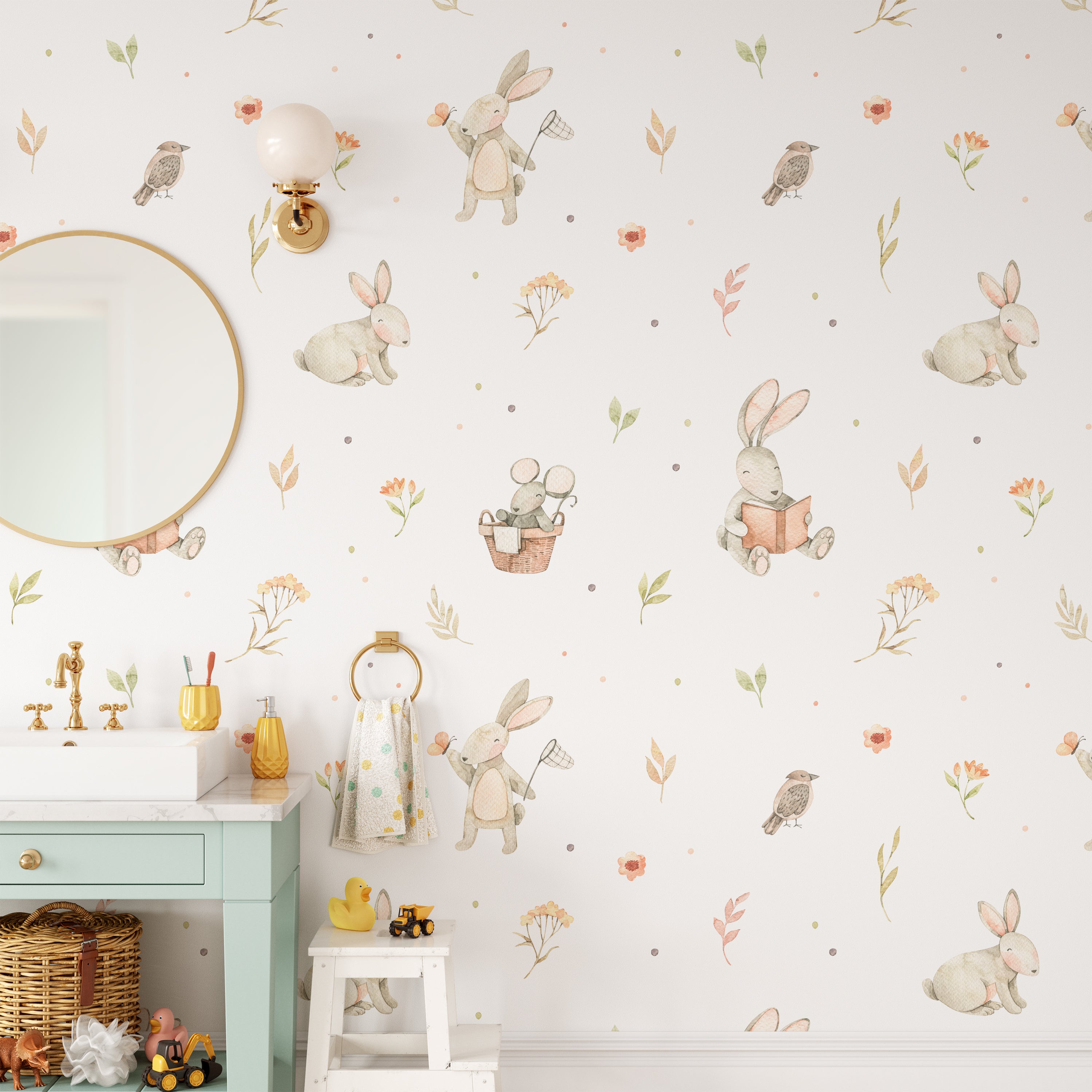 A nursery room decorated with the Watercolour Bunnies Wallpaper on the wall, creating a delightful scene with rabbits engaging in quiet play and exploration amongst flora and fauna. The space is complemented by a round mirror, a mint-colored dresser, and whimsical children's decor.