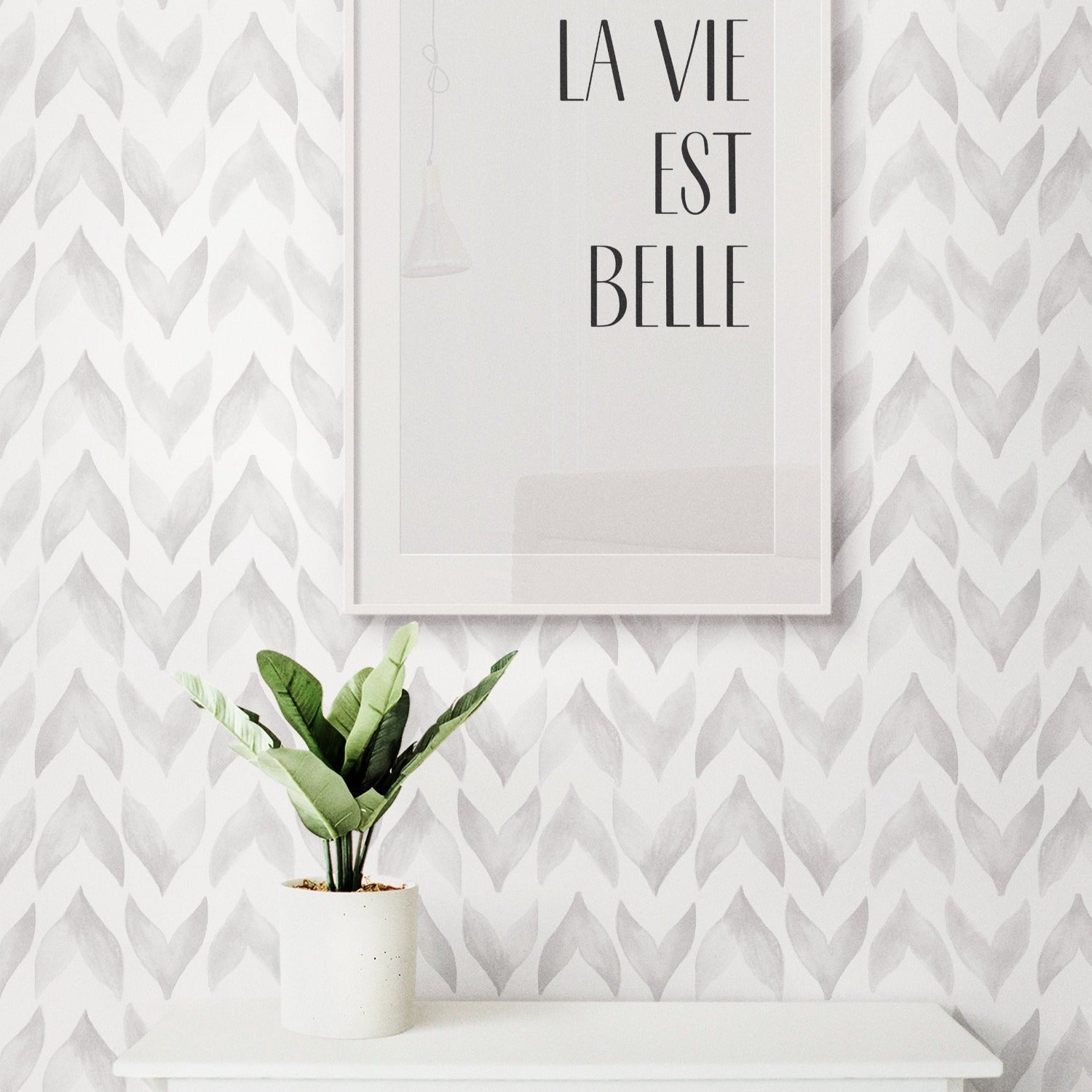 An interior decor scene showing Moroccan Tile Wallpaper applied on a wall, complemented by a framed poster reading 'LA VIE EST BELLE' and a potted plant on a white shelf, suggesting a chic and modern living space.