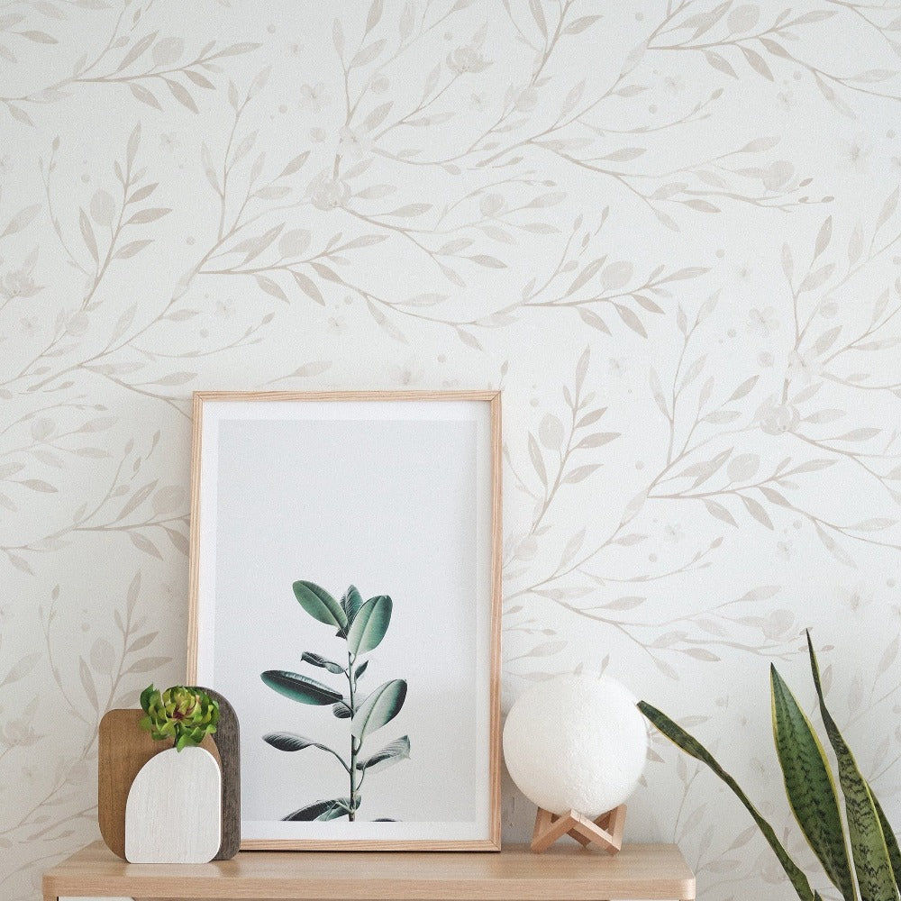 A cozy corner with 'Spring Bird' wallpaper enhancing the space with its gentle botanical print, framed artwork, and indoor greenery adding warmth