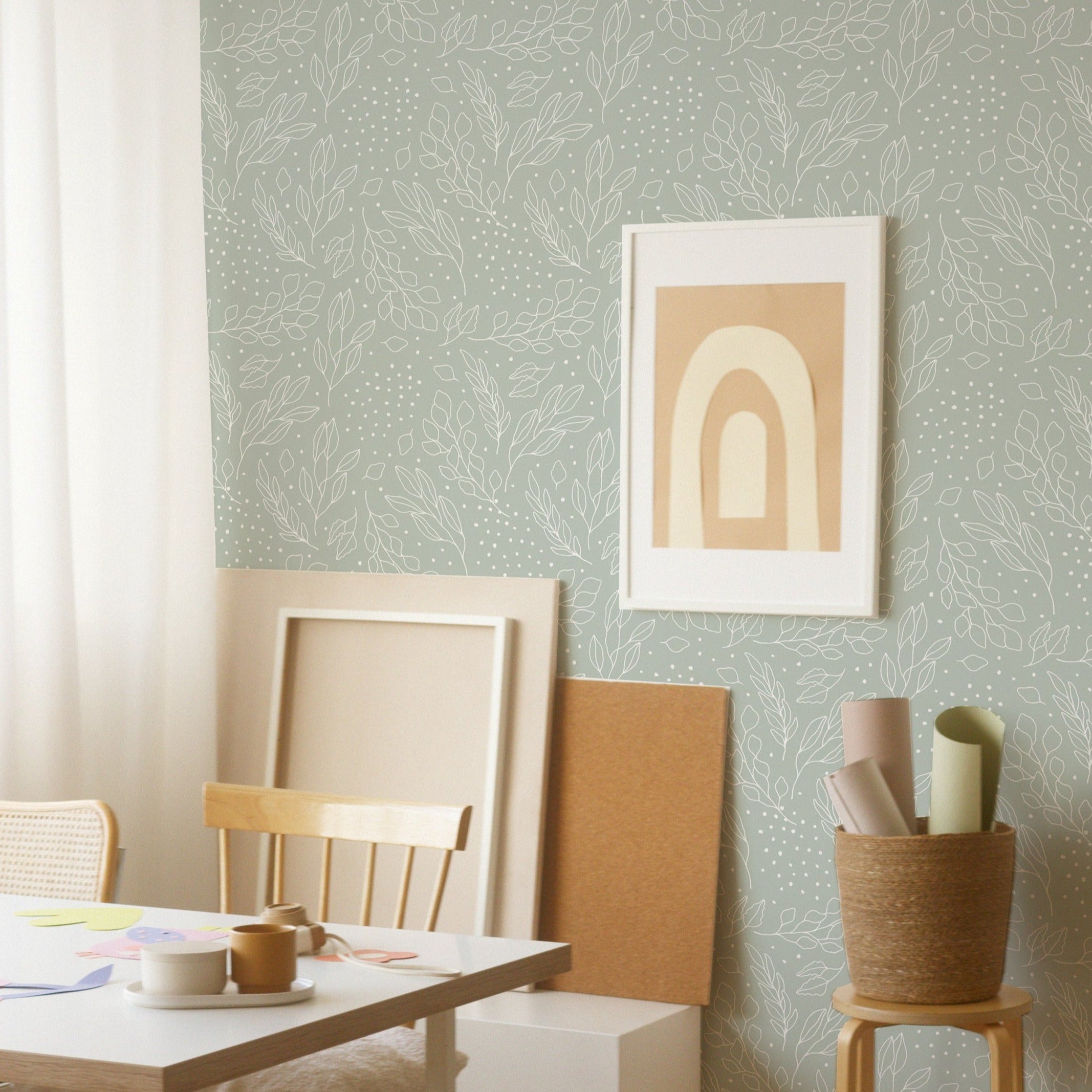 Creative workspace enhanced by the Ferns and Leaves Wallpaper, which adds a calm and nature-inspired vibe with its soft green leafy pattern. The scene includes a simple wooden desk, a chair, and inspirational art, ideal for fostering creativity