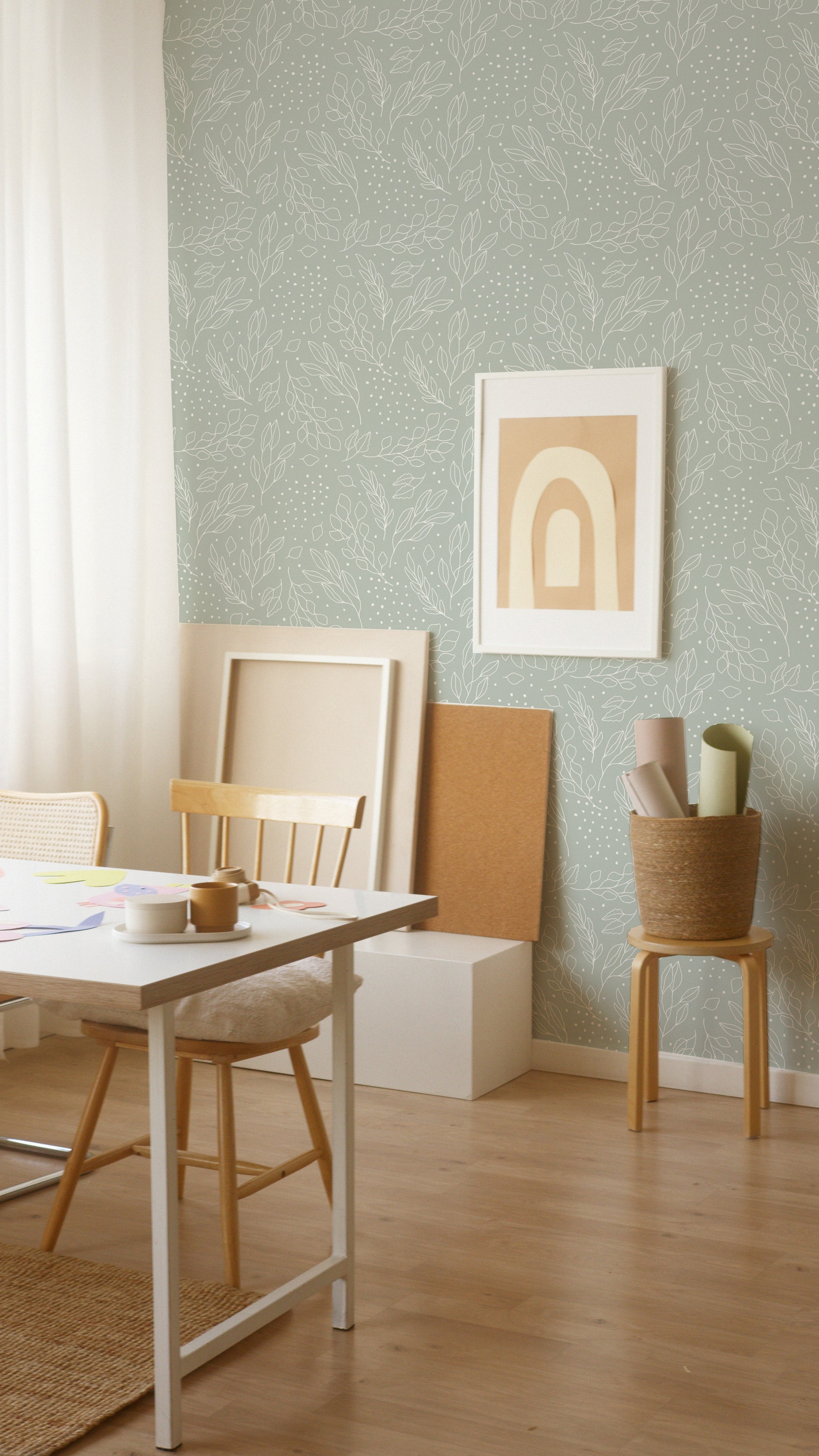 Creative workspace enhanced by the Ferns and Leaves Wallpaper, which adds a calm and nature-inspired vibe with its soft green leafy pattern. The scene includes a simple wooden desk, a chair, and inspirational art, ideal for fostering creativity