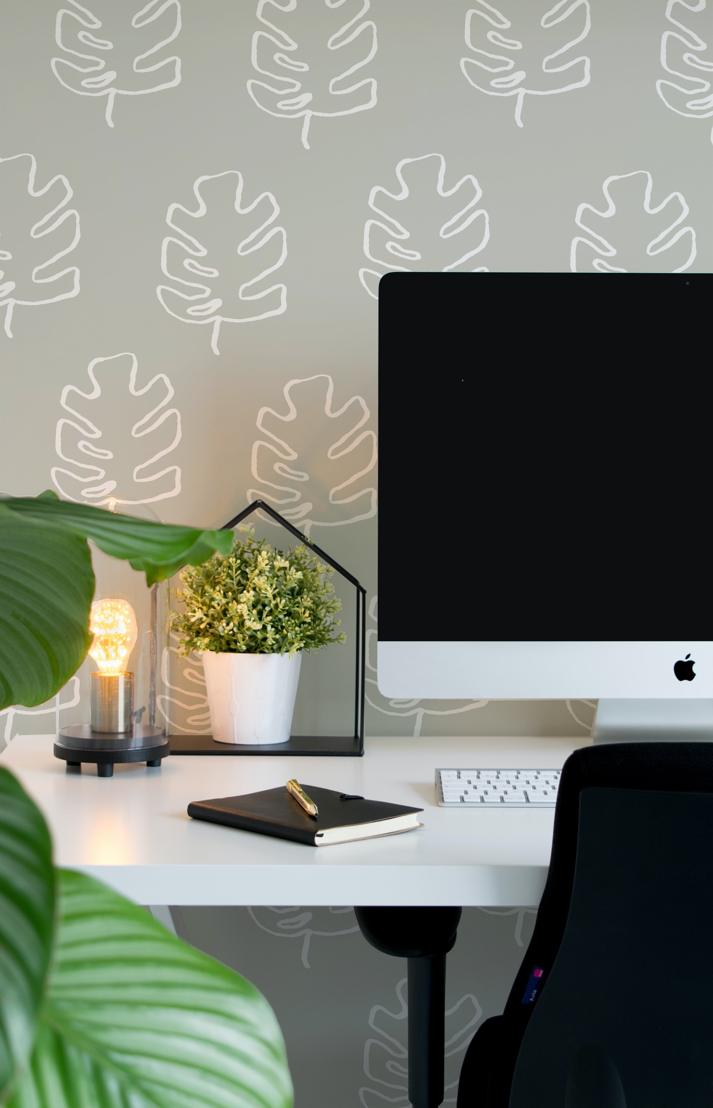 A stylish home office setup enhanced by the Palm Leaves Wallpaper, featuring a simple and elegant white palm leaf design on a grey backdrop. The wallpaper adds a touch of nature-inspired tranquility to the space, complemented by a modern desk and ambient lighting.