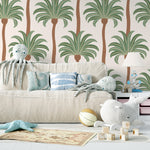 A cozy children's play area adorned with Tropical Palm Dreams wallpaper, featuring a lively pattern of palm trees, complemented by a plush sofa filled with marine-themed toys and a nautical rug