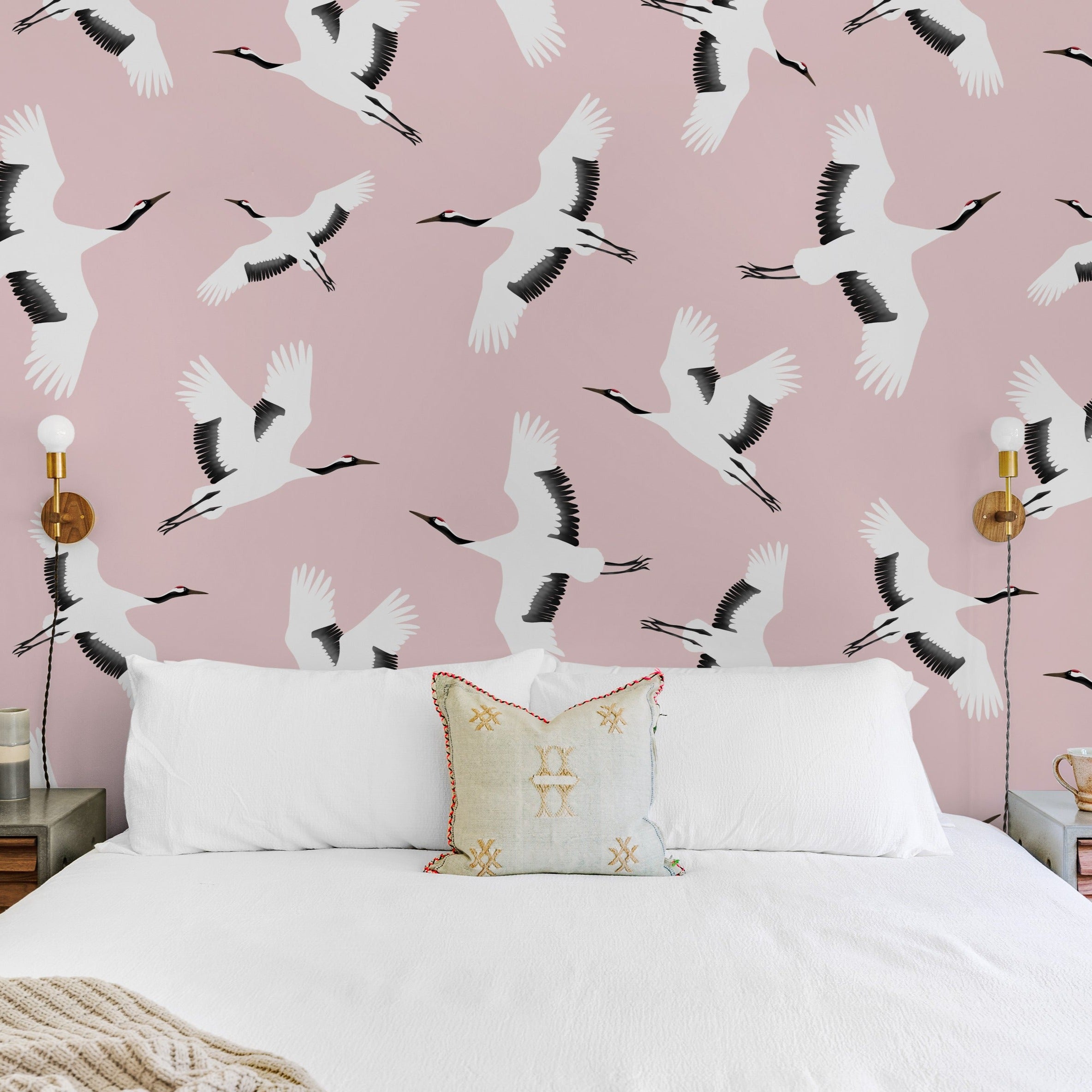A stylish bedroom showcasing the 'Kids Crane Wallpaper,' with its delicate depiction of white cranes flying over a blush pink background, complementing a modern and serene decor style