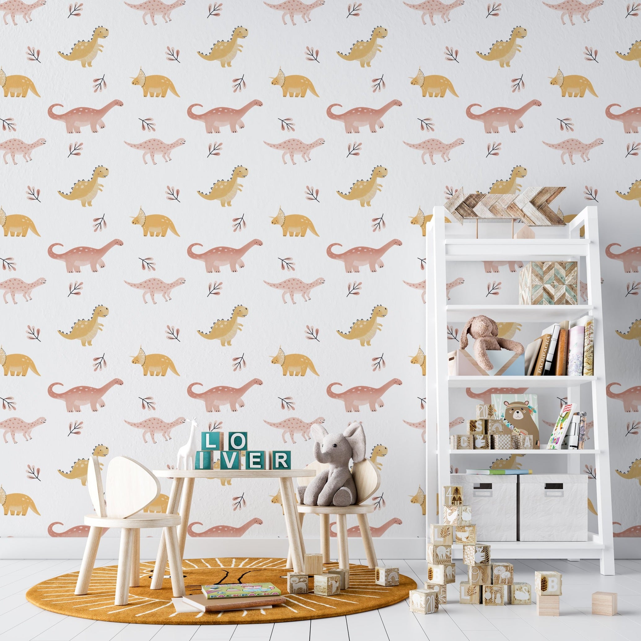 Nursery room featuring 'Dino World Kids Wallpaper' with a pattern of pale pink and yellow dinosaurs and delicate foliage on a white background. The room includes a small children's table and chair set, a white shelf with books and toys, enhancing a cozy and imaginative play space.