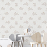 A nursery room wall covered with 'Nursery Bunny Wallpaper,' depicting adorable beige bunnies interspersed with golden dots on a light background, enhancing the tranquil and cozy ambiance of the space