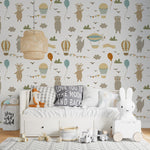 Child’s bedroom wall adorned with Hot Air Balloon Wallpaper, showcasing a variety of cute animals in hot air balloons and playful kites among clouds, creating a serene and imaginative backdrop that complements the room's cozy and soft furnishings.