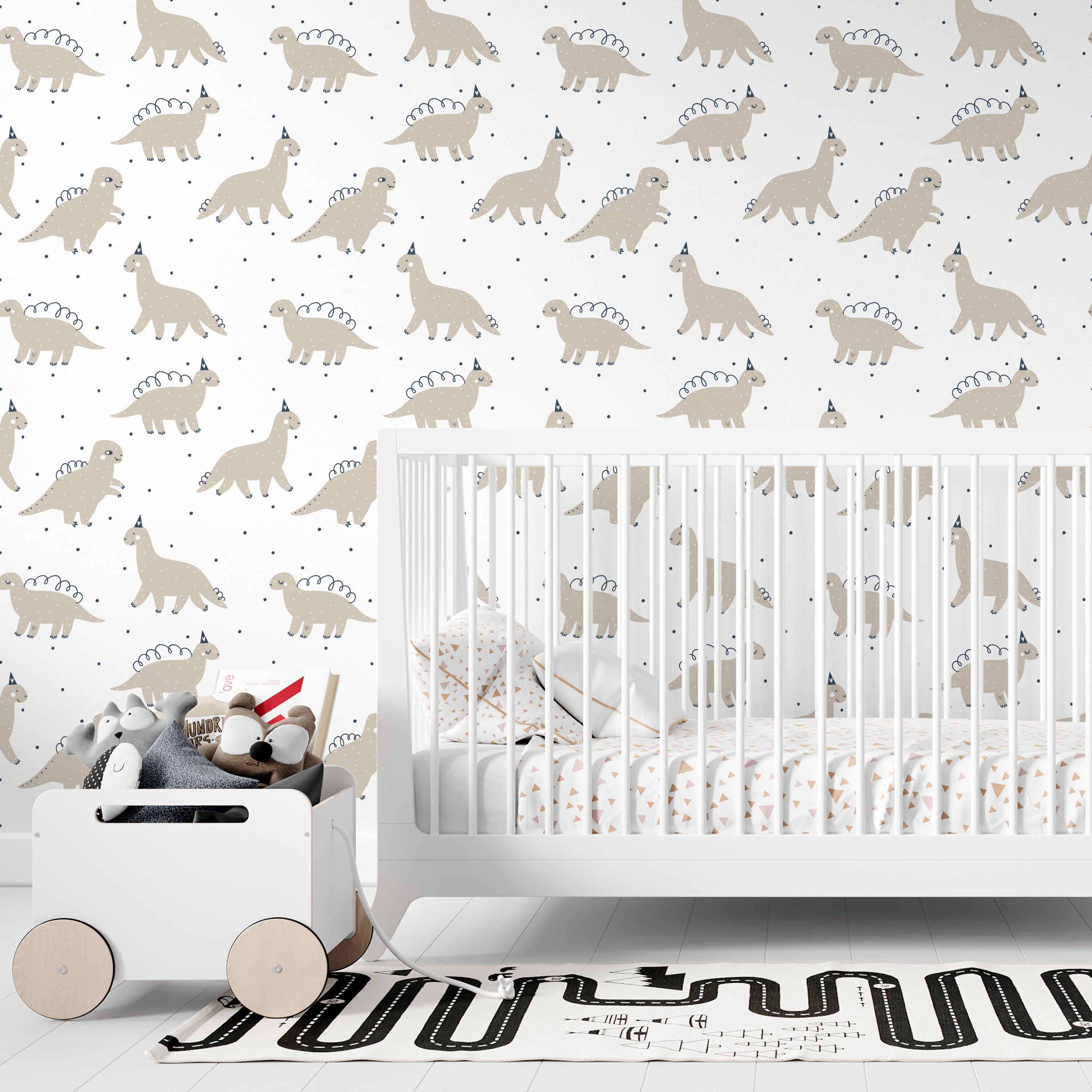Dino Party Wallpaper installed in a children's nursery, featuring rows of friendly dinosaurs in party hats. The wallpaper complements a modern white crib and playful room accessories, creating a fun and inviting atmosphere for young children.