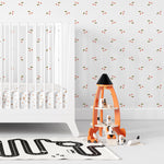A child's nursery room wall covered with a minimalist cherry wallpaper, displaying small red cherries and green leaves on a white background, creating a playful and soothing environment