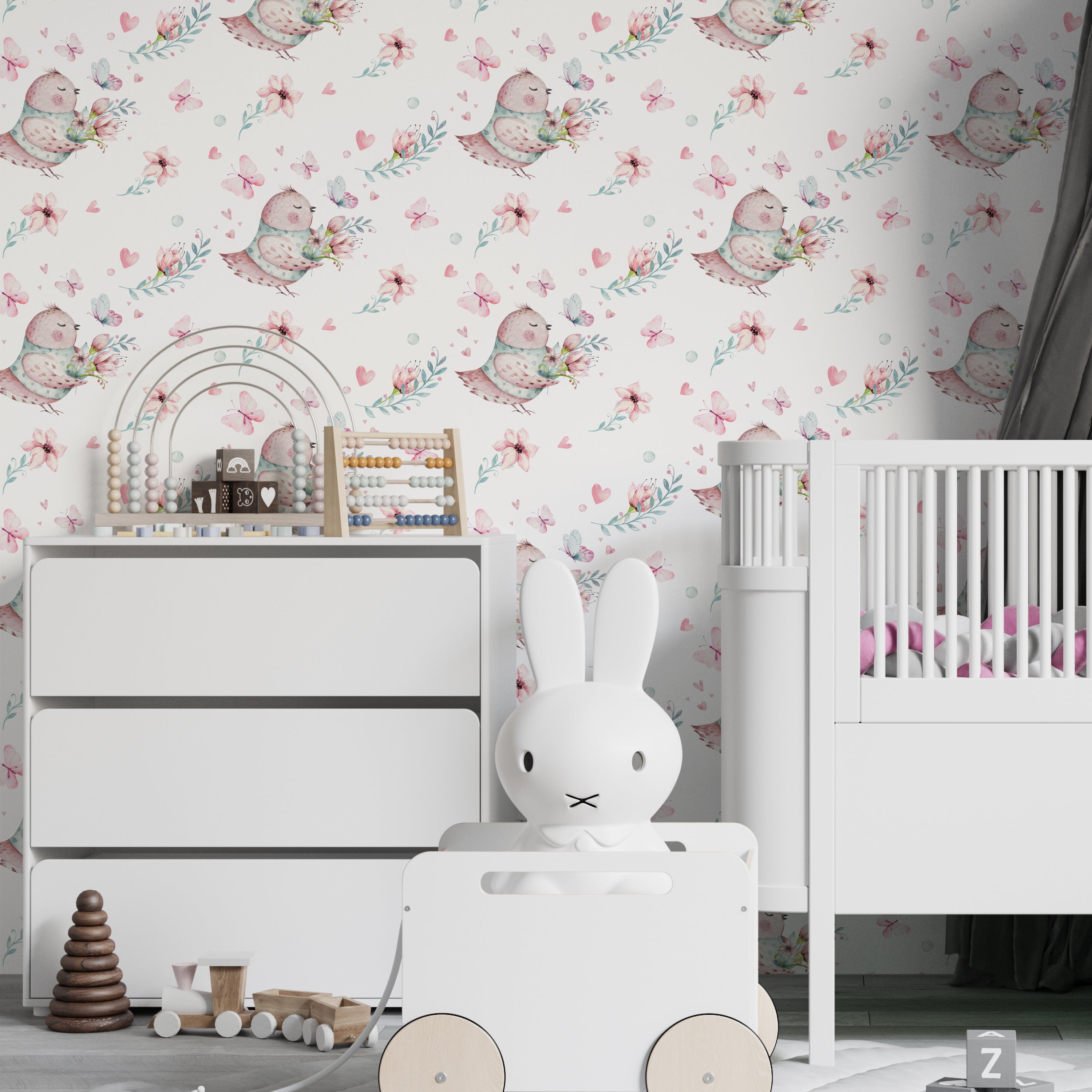 A children's nursery featuring walls covered with 'Fairy and Flowers Wallpaper IV'. The wallpaper displays a playful pattern of birds with leafy wings, scattered flowers, and butterflies, creating a magical and serene atmosphere. The room includes modern white furniture and playful children's toys