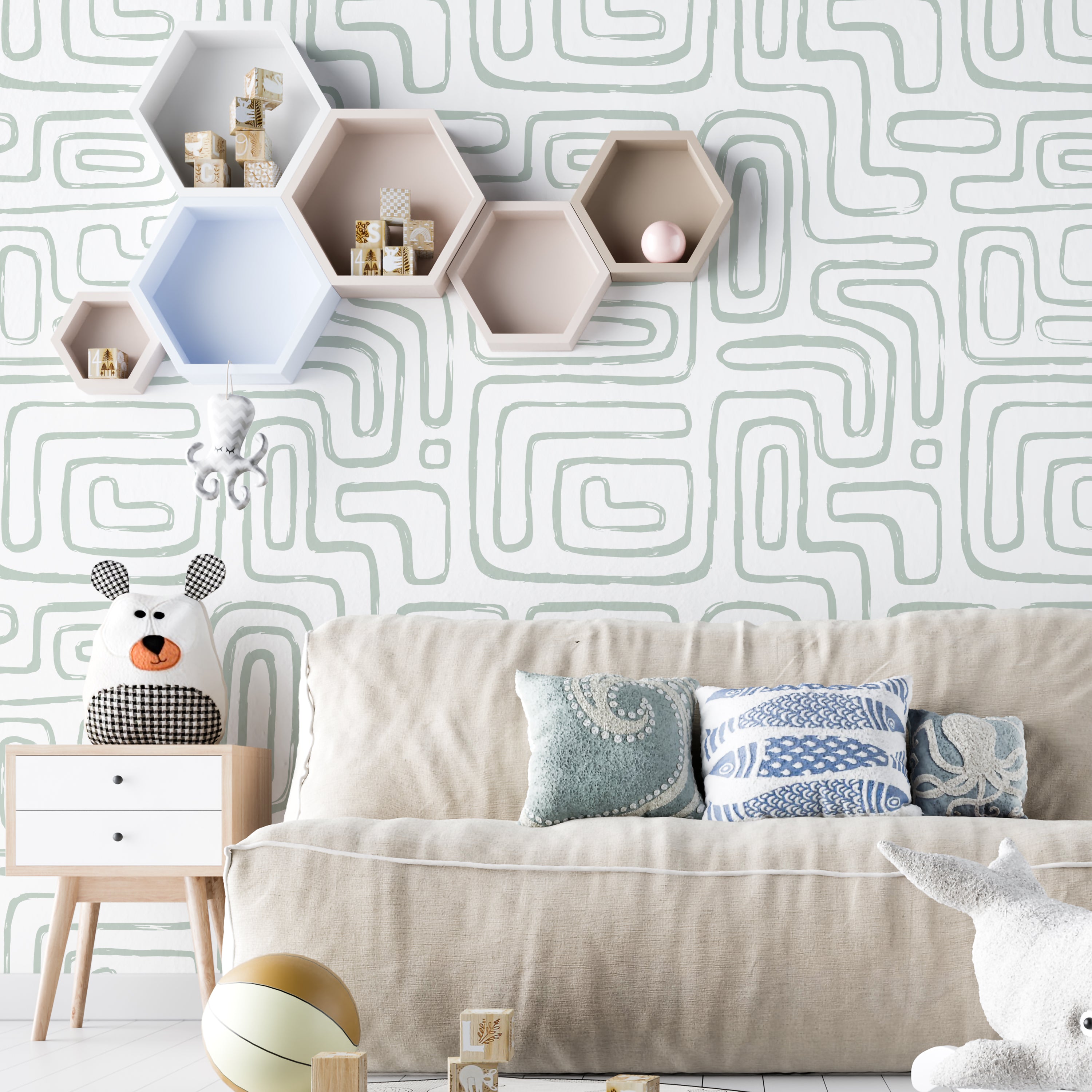 A stylish living room setting showcasing the Organic Wallpaper 4 on the walls, enhancing the space with its distinct seafoam green abstract shapes. The room includes a beige sofa adorned with various pillows, a whimsical stuffed animal on a small wooden table, and hexagonal wall shelves in soft pastels
