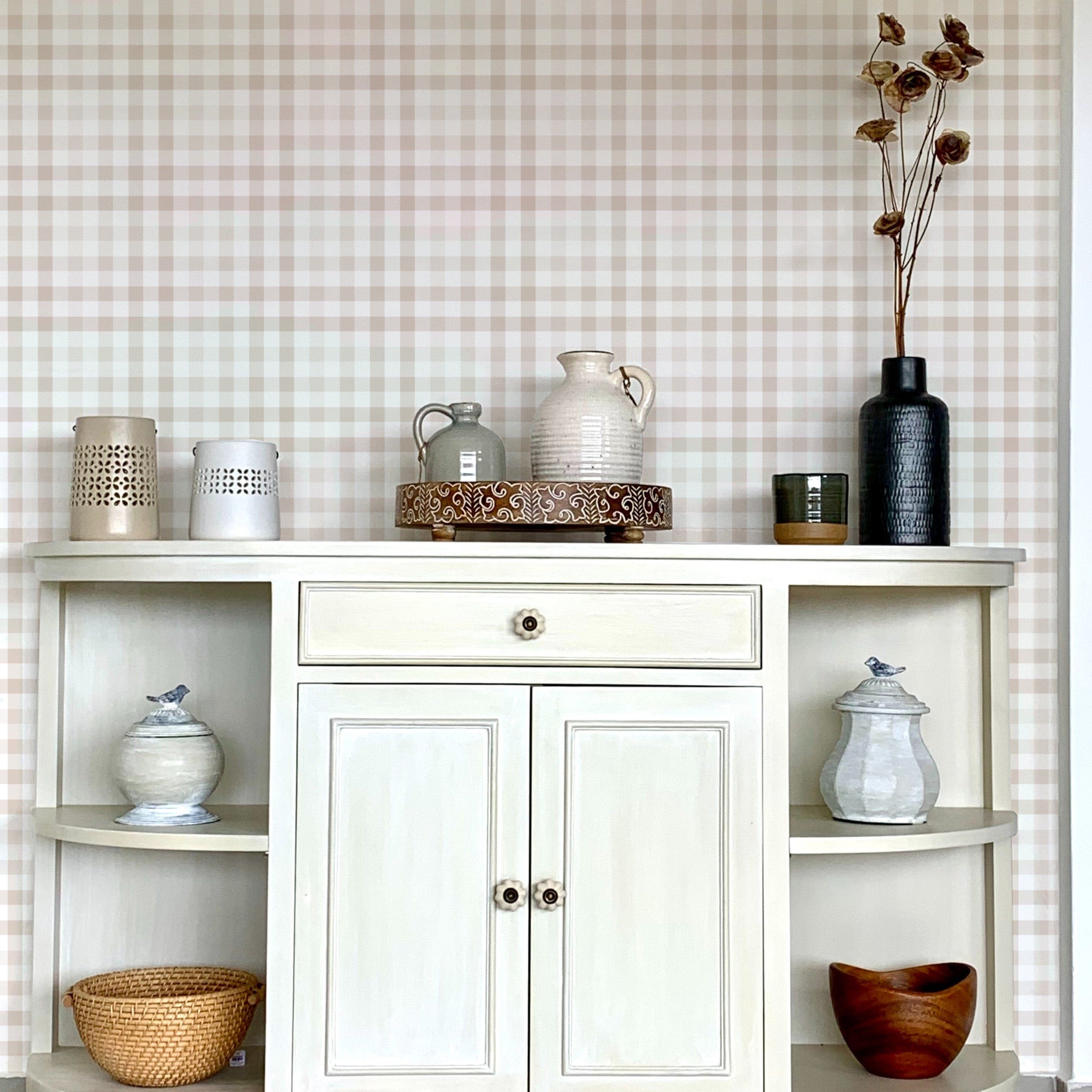 A well-arranged shelf against a backdrop of beige and white gingham wallpaper. The shelf displays various decorative items including vases, a basket, and ceramic jars, contributing to a rustic and homely aesthetic.