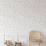  light-filled classic room featuring beige dainty minimal floral wallpaper, with elegant white wainscoting below and decorative frames, complemented by a rattan chair and woven baskets