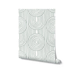 A roll of Zen Abstract Wallpaper, elegantly unrolled at one corner to reveal its calming pattern of sage concentric circles on a white background, representing a sophisticated choice for adding a peaceful ambiance to any room