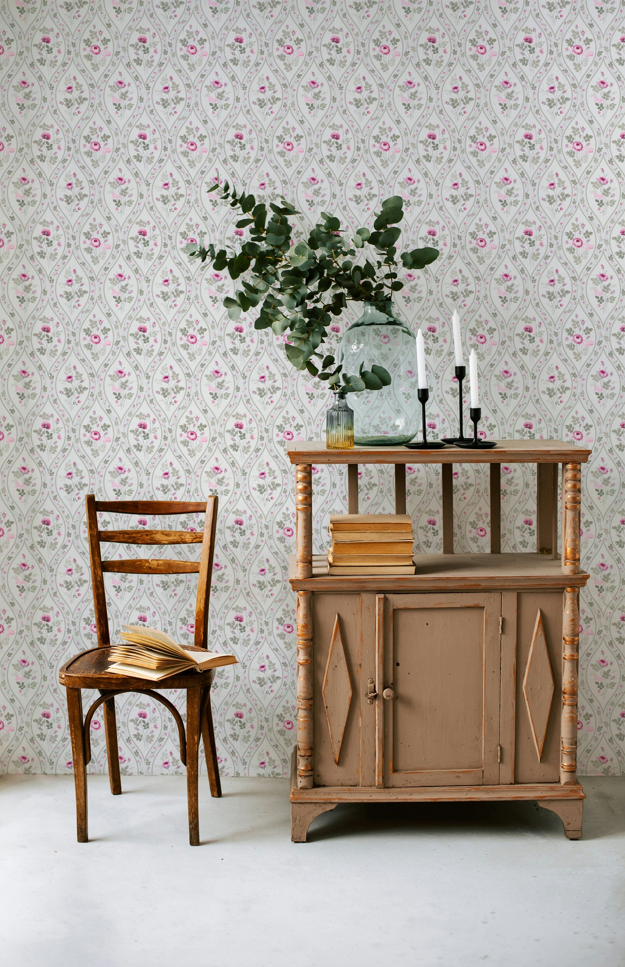 A traditional interior setting showcasing the Vintage Charm Wallpaper, where subtle gray teardrops form a classic backdrop to pink roses and green foliage. The vintage furniture and rustic décor enhance the timeless appeal of the wallpaper, creating a cozy and nostalgic space.