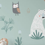 A close-up of the "Kids Wallpaper - Forest Critters - 25 inches" showcases its intricate design. The wallpaper depicts various woodland creatures such as owls and squirrels, along with flora and fauna in muted earth tones on a teal backdrop, perfect for adding a touch of nature's serenity to any child’s room.