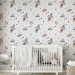 A charming nursery featuring the Space Craze Wallpaper, decorated with whimsical illustrations of rockets, UFOs, planets, and stars on a light background. The room includes a white crib draped with a soft, textured blanket, creating a playful yet serene space for a child.