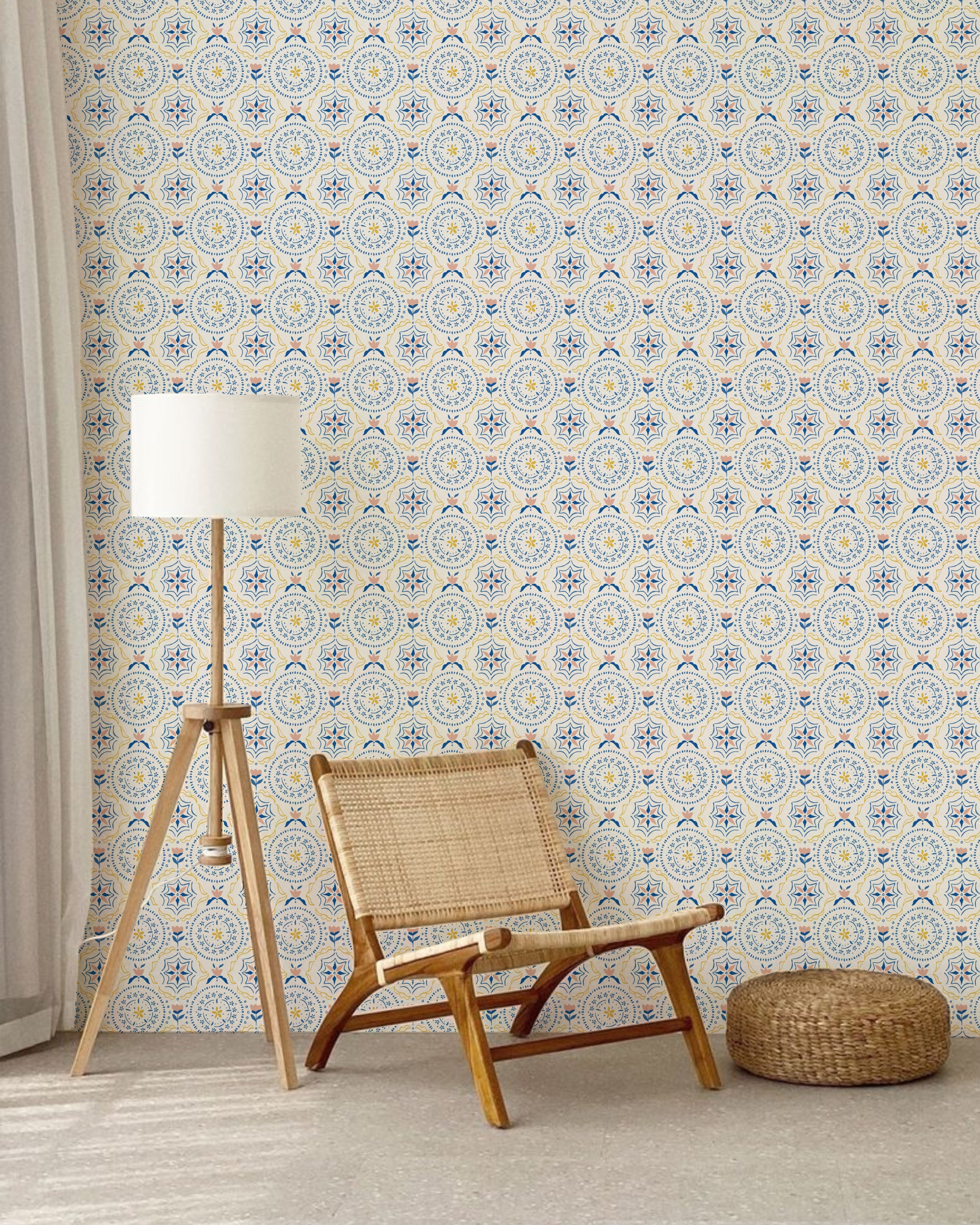 A cozy living area featuring a rattan chair and wooden floor lamp against a wall covered in wallpaper with a star-shaped floral design in blue and yellow