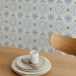 Elegant dining setting with a table set for one, against a wallpaper adorned with a blue and yellow starry floral pattern on a light background.