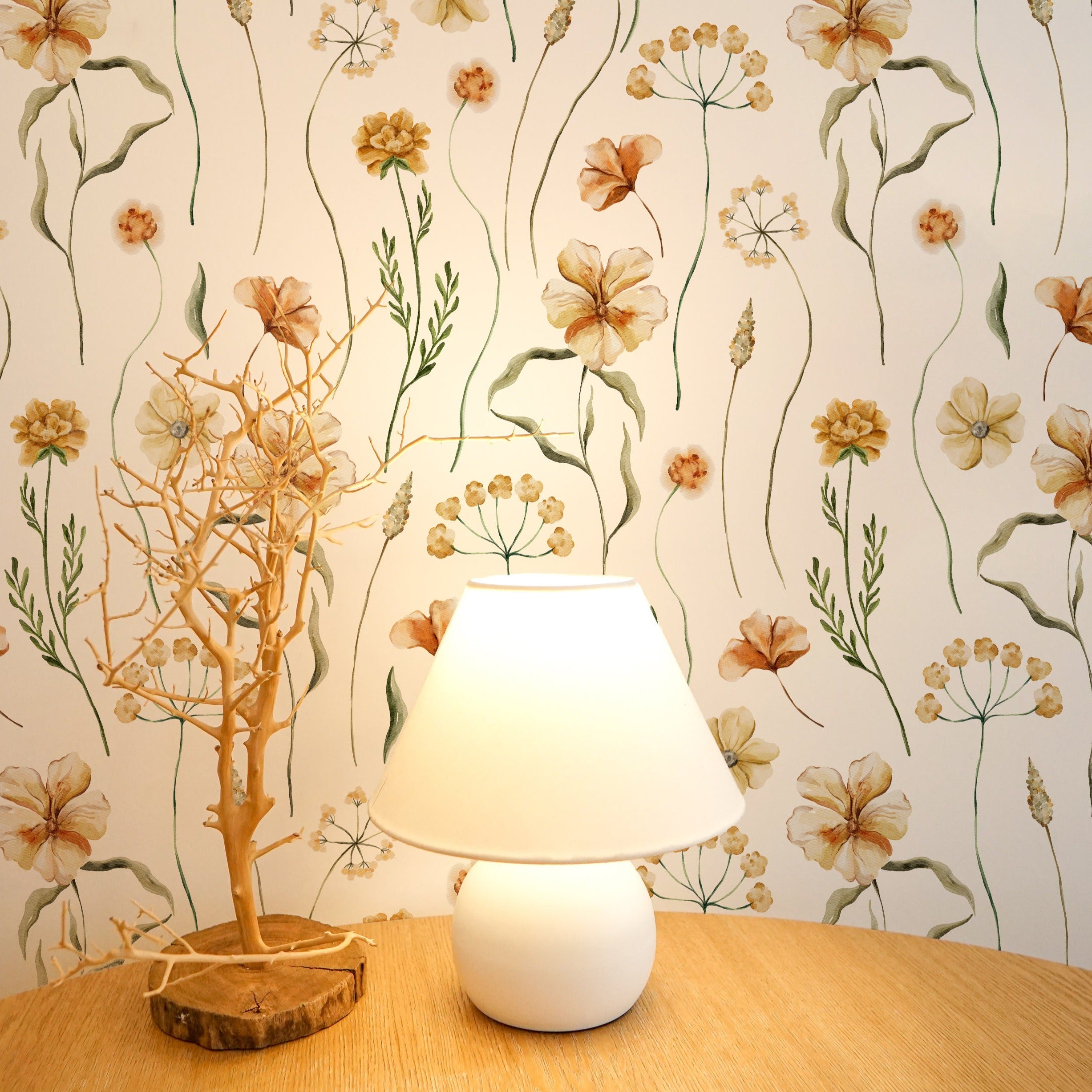 A serene bedside setup with the Warm Glow Floral Wallpaper providing a tranquil background. A simple white lamp on a wooden nightstand complements the wallpaper’s floral motifs, creating a peaceful and relaxing bedroom ambiance