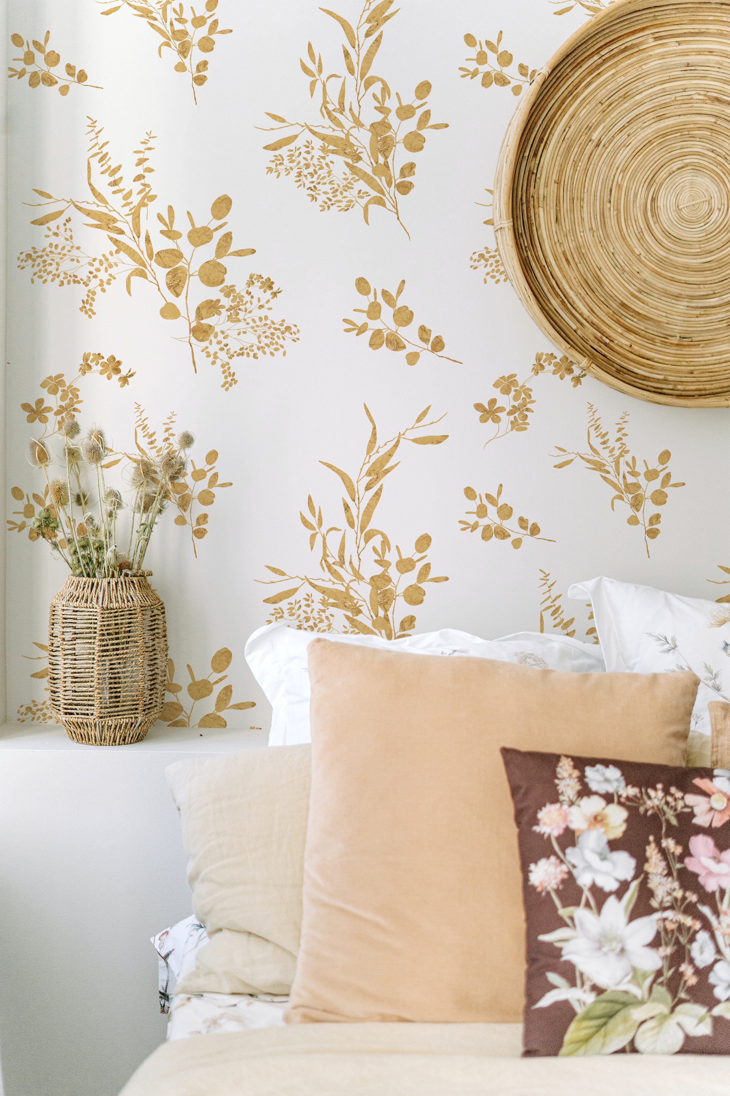 A tranquil corner of a room decorated with Golden Greenery Wallpaper, paired with a wicker basket holding dried flowers and a bamboo mat rolled up against the wall, enhancing the room’s organic and peaceful feel.