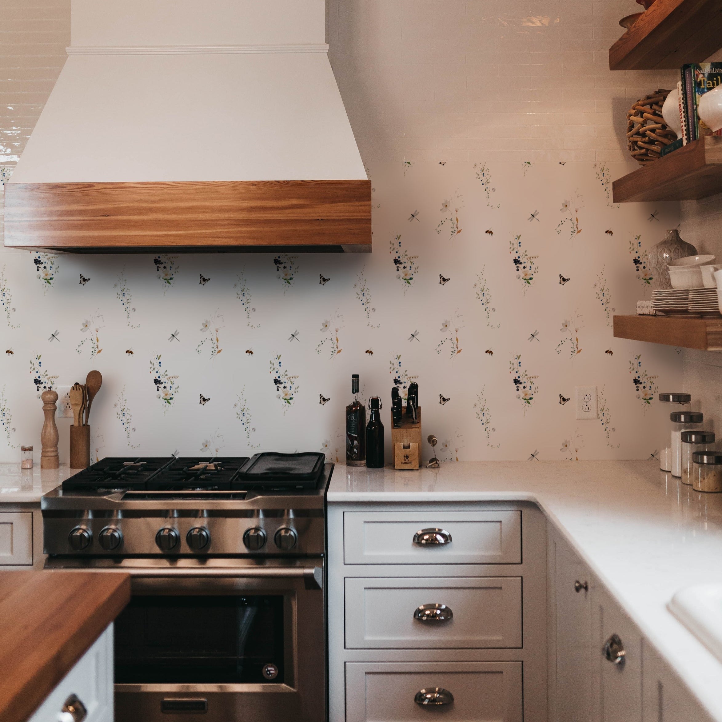 A modern kitchen setup with the "Berry Spring Wallpaper" providing a lively backdrop. The kitchen features sleek cabinetry and a professional-grade stove, with the playful and naturalistic wallpaper pattern adding a touch of whimsy and charm.
