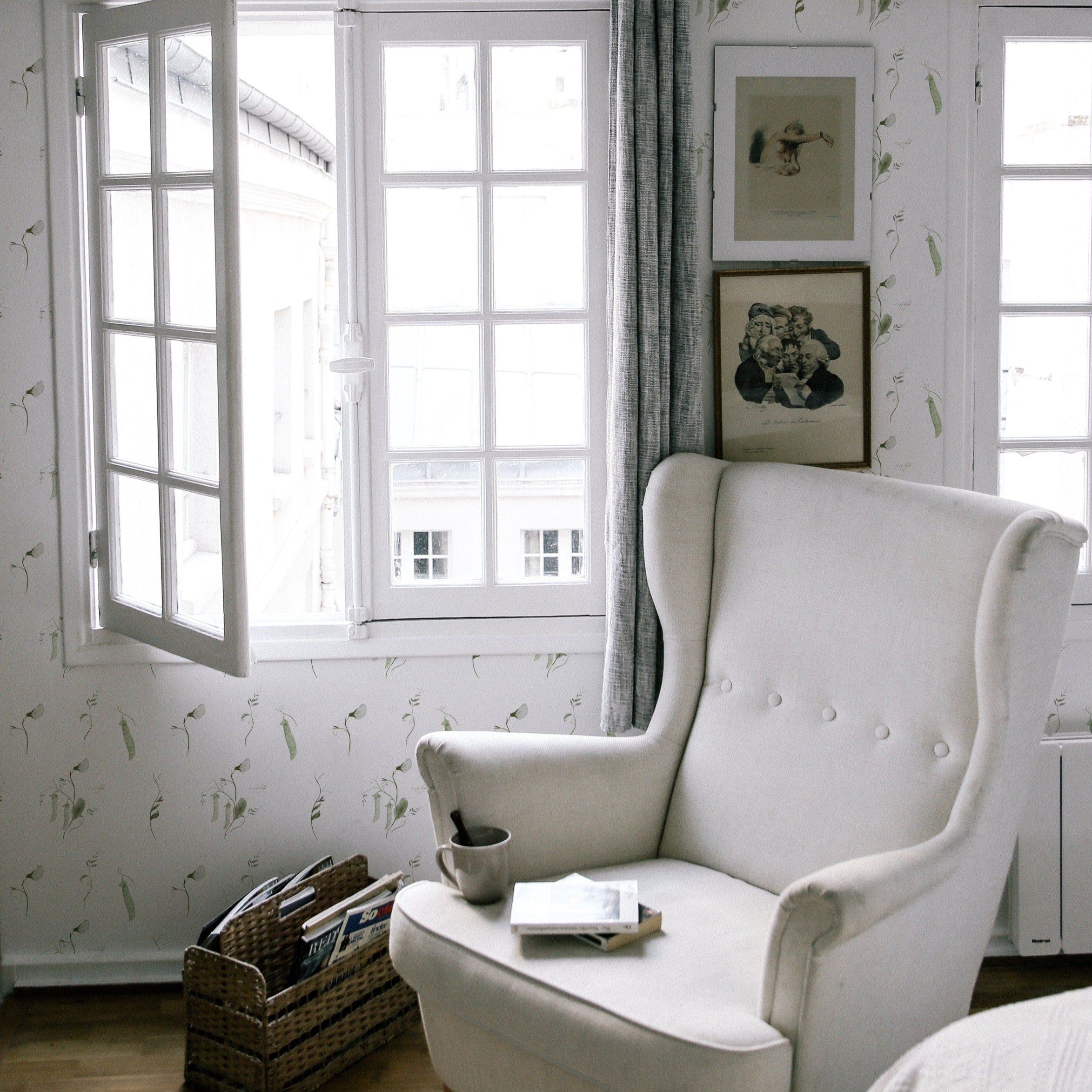 A serene reading nook with a large, plush armchair positioned near a bright window, surrounded by walls adorned with snow pea wallpaper. The scene exudes a calm, inviting atmosphere enhanced by natural light and minimalist decor.