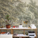A vibrant workspace with a long wooden desk cluttered with office supplies, facing a wall mural depicting a serene 18th-century landscape scene from Eext with detailed trees and a pastoral setting.