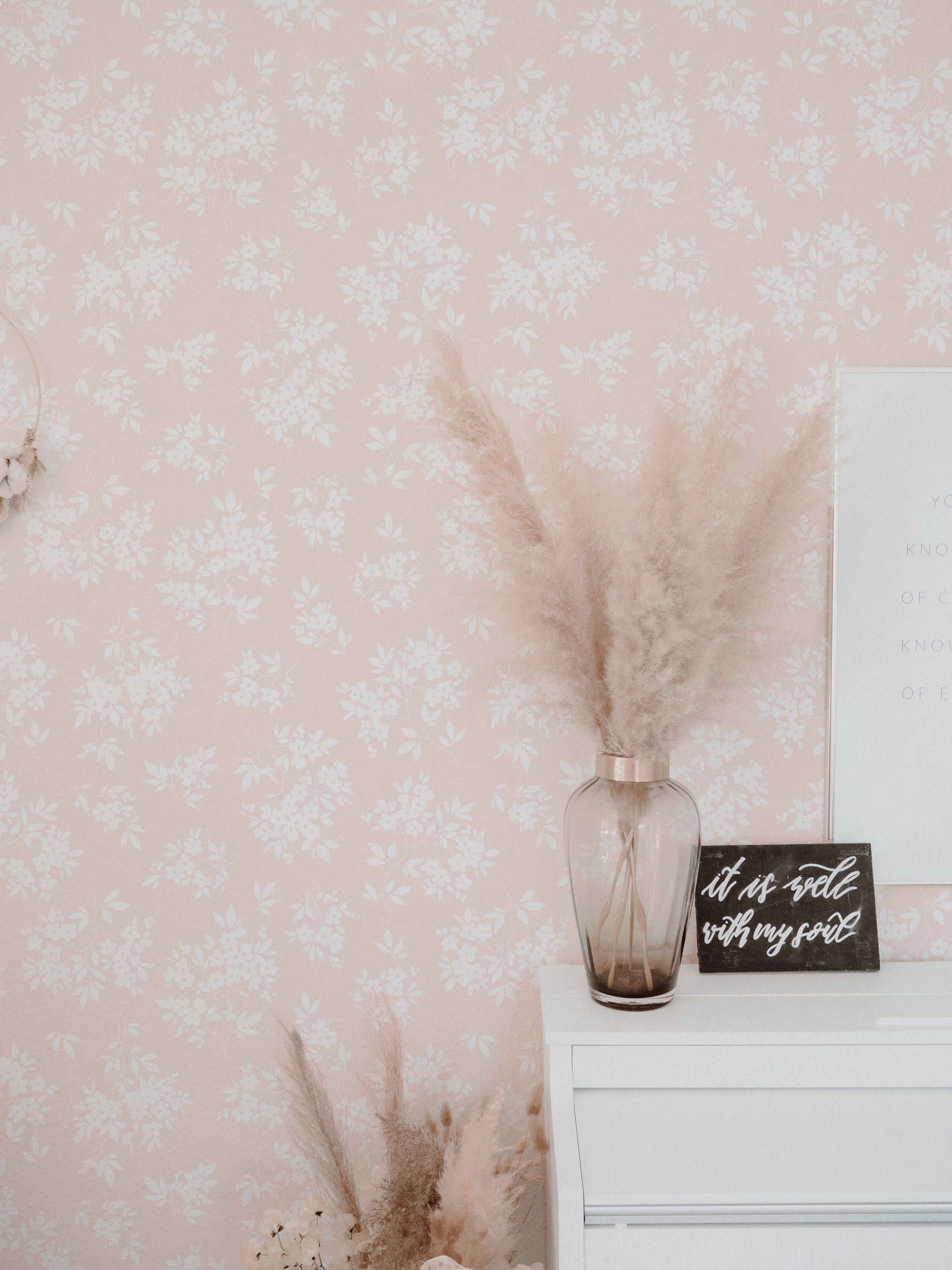 A stylish room corner featuring the Vintage Garden Floral Wallpaper in champagne. The wall is complemented by a rustic vase filled with pampas grass and a motivational quote sign, creating a cozy and inspirational space.