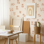 A creative workspace enhanced with Chaton Wallpaper displaying playful kitten illustrations in beige and brown on a peach backdrop. The room features a minimalist white desk, a light wooden chair, and various art supplies, creating an inspiring environment for creativity.