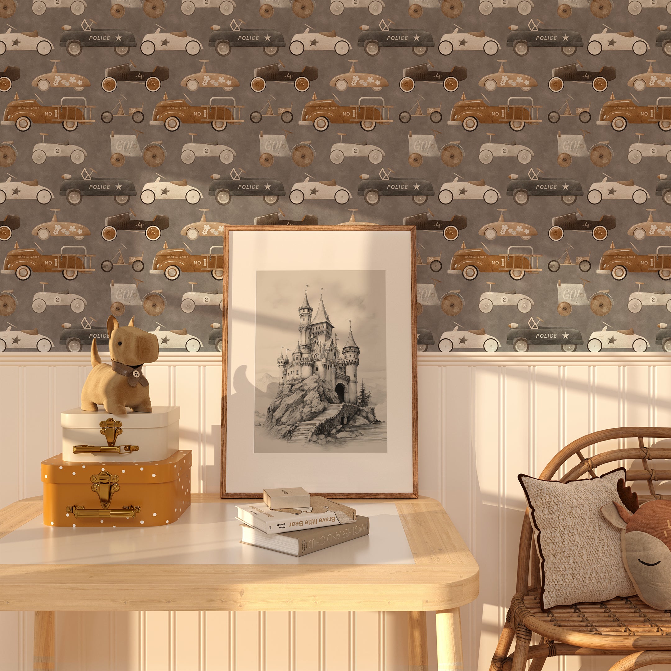 A charming room with the Retro Wheels Wallpaper adorning the walls. The wallpaper displays a repeating pattern of vintage cars in brown, gray, and white. A wooden table with a framed sketch of a castle, a plush dog toy, and a stack of books is placed against the wall.