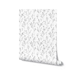 Rolled up Dainty Black Floral Wallpaper with a seamless pattern of delicate black floral illustrations on a white background.