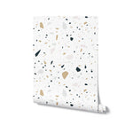 A roll of Stone Terrazzo Wallpaper showcasing its full design, with speckled geometric shapes on a crisp white background, bringing a modern twist to classic terrazzo style.