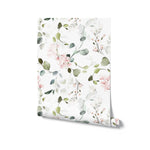 A close-up view of the Pink Floral & Herbs Wallpaper roll, displaying the soft watercolor blooms and greenery on a white background. The wallpaper captures the essence of a tranquil garden, ideal for infusing spaces with floral charm and a sense of peace.