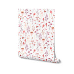 A roll of Blushing Floral Wallpaper partially unrolled, showing the intricate floral designs in hues of pink, red, and beige on a light background, perfect for adding a delicate and fresh look to any room.