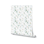 A rolled piece of Blossom Breeze Wallpaper, illustrating the delicate floral design of small blue and yellow flowers scattered among green foliage on a white background, perfect for adding a touch of spring to any interior.