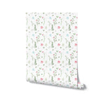 A roll of Spring Field Wallpaper - VIII displaying its continuous pattern of pink, blue, and yellow flowers with green leaves on a white background, perfect for adding a touch of spring to any room.