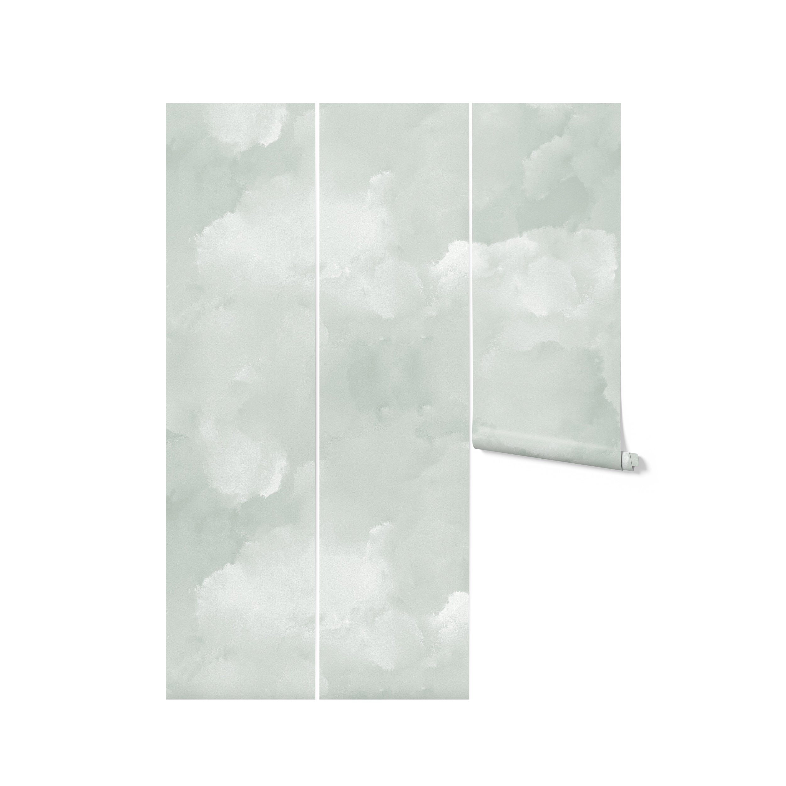 Three vertical strips of light sage cloud mural wallpaper unrolled and displayed, showcasing the soft, cloudy patterns in shades of sage green and white.