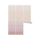 A display of the Blush Gradient Wallpaper in three vertical panels, showing the gradient effect from top to bottom. The wallpaper roll is also shown partially unrolled, emphasizing its texture and color gradient.