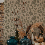 A warm and inviting room decor accentuated with the Little Flowers Wallpaper. The room features a vintage wooden dresser adorned with autumn-themed decorations including dried flowers, pumpkins, and colorful vases. The floral wallpaper adds a soft, botanical backdrop that complements the rustic and seasonal elements of the room's decor.