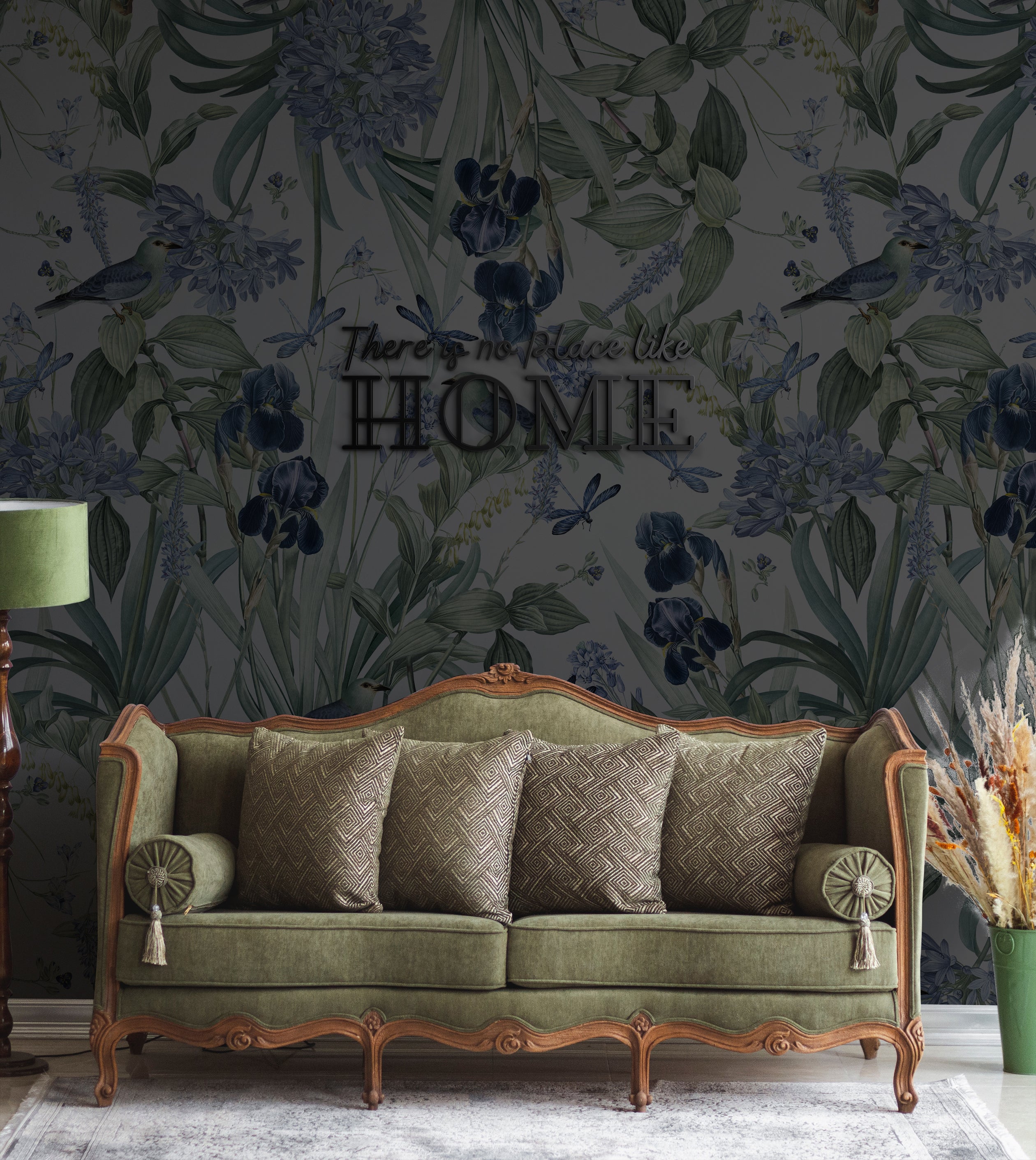 A stylish living room with a vintage green sofa, patterned cushions, and a floor lamp. The wall behind the sofa is adorned with Mint Floral Wallpaper on a slate background, showcasing detailed illustrations of leaves, blue flowers, birds, and dragonflies.