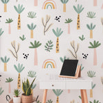 A cozy workspace enhanced by the Tropical Kids Room Wallpaper. The wallpaper covers the wall behind a stylish white desk, adorned with a small chalkboard and various houseplants in cute containers. The playful and bright patterns of the wallpaper provide a stimulating backdrop, encouraging creativity and joy in a child's learning environment.