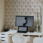 A modern home office setup with 'Scallop Mosaic Wallpaper' adorning the walls, featuring a repetitive beige and white scalloped design. The room is neatly organized with a white desk, a stylish ergonomic chair, and a desktop setup, offering a calm and chic workspace.