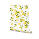 Rolled view of the Lemon Floral Wallpaper displaying the cheerful pattern of yellow lemons, green leaves, and white flowers on a white background, ready for application.