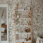 A room adorned with the "WildFloral Wallpaper - 75"," creating a tranquil and romantic atmosphere. A wooden shelf displays various homely items, further accentuating the wallpaper's delicate, hand-painted floral design that brings a touch of nature indoors.